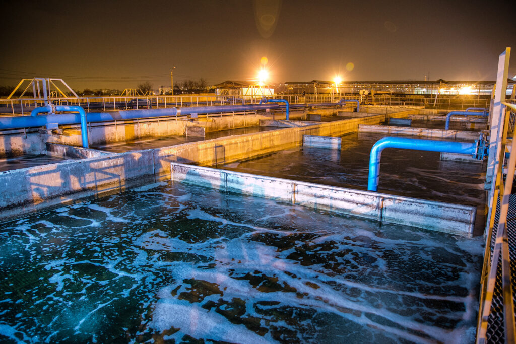 Modern wastewater treatment plant of chemical factory at night. Water purification tanks copy