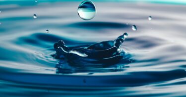 Water droplet splashing into blue water