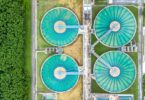 Aerial view of large circular wastewater treatment tanks surrounded by greenery