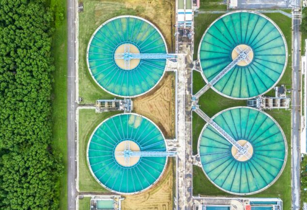 Aerial view of large circular wastewater treatment tanks surrounded by greenery
