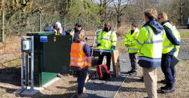 Engineers and technicians gathered around water monitoring and dosing equipment during a site installation.