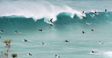 Surfers riding waves off the Queensland coast, near the site of a sewage treatment plant upgrade.