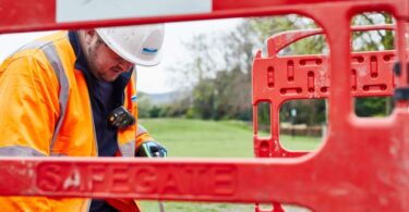 Yorkshire Water engineer in high-visibility clothing working behind safety barriers during water mains upgrade works.