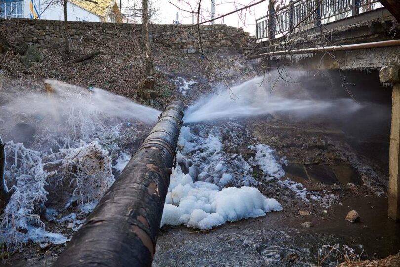 Technician using acoustic equipment for leak detection in an urban water network