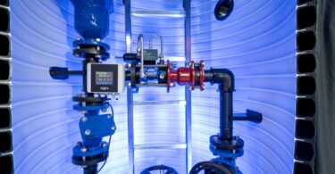 Flow control components and valves inside a GF/VAG demonstration chamber showing integrated piping, sensors and metal valve assemblies.