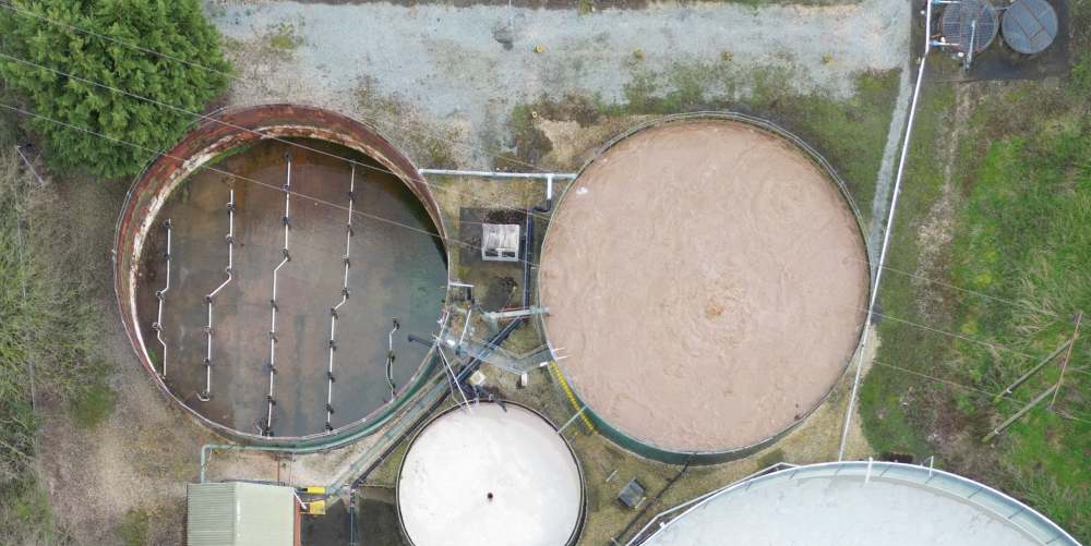 Aerial view of multiple effluent treatment tanks showing an old tank and the upgraded aerated tank in operation.