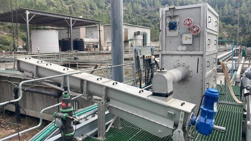 Mechanical screening equipment installed at an outdoor wastewater treatment plant, showing stainless steel screening unit, conveyor and associated pipework.