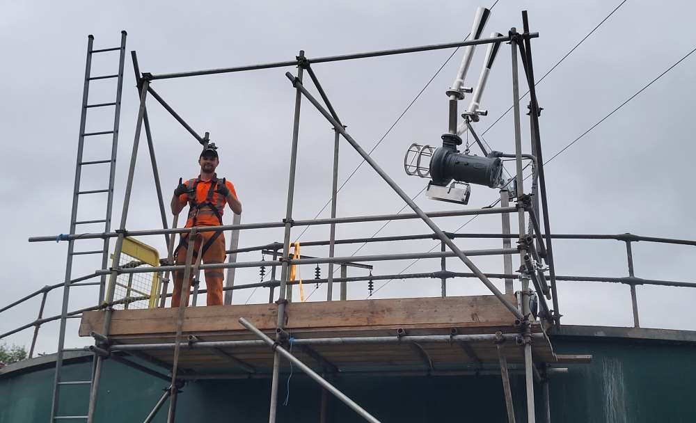Engineer standing on scaffold platform beside a mounted Landia aeration unit installed without crane access.