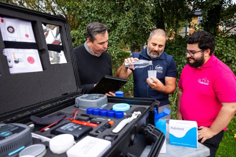 Richard King, Willie Plowman, and Adam Ali testing water samples with Palintest&rsquo;s Wagtech Potalab+ water testing system beside the River Dart.