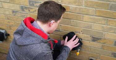 A South East Water engineer wearing a hearing aid inspects an outdoor water fitting, representing the company’s commitment to supporting deaf and hard-of-hearing customers.
