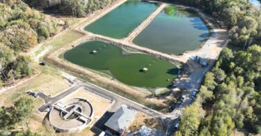 Aerial view of the Gravel Ridge facility showing the new mechanical treatment plant alongside the original wastewater lagoons used for equalisation and wet-weather flow storage.