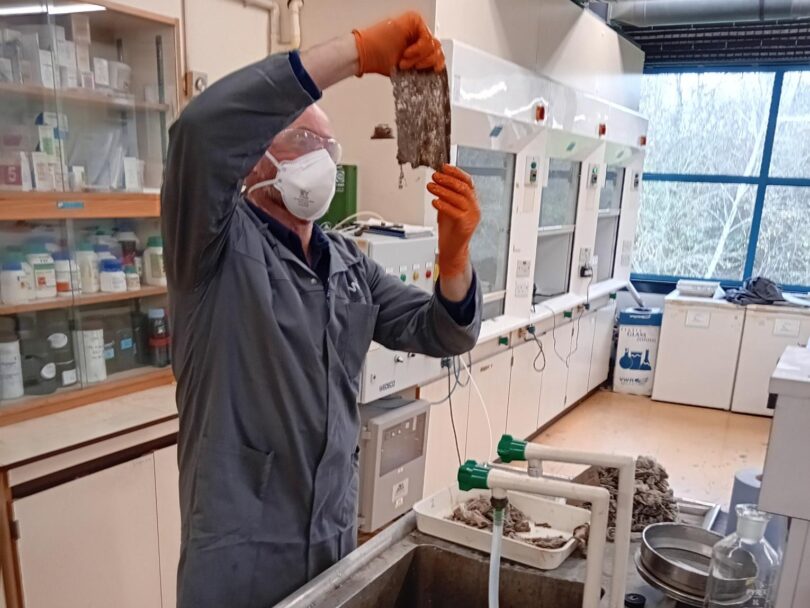 Person wearing protective equipment examining wet wipe samples in a laboratory during analysis for the WRc waste autopsy.