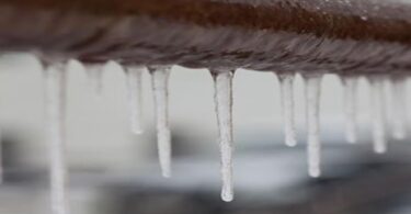 Icicles hanging from a frozen water pipe during cold weather.