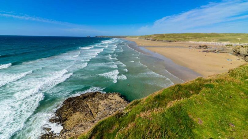 A South West England beach with clear blue water and clean sandy shoreline, illustrating the region&rsquo;s high bathing water quality.