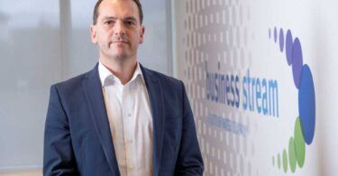 Tom Abel, Director of Sales at Business Stream, standing in front of a Business Stream branded display.