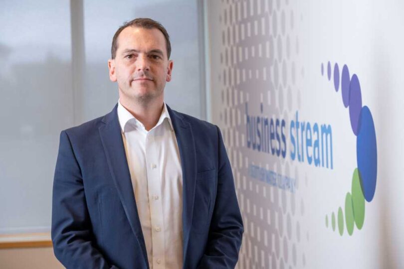 Tom Abel, Director of Sales at Business Stream, standing in front of a Business Stream branded display.