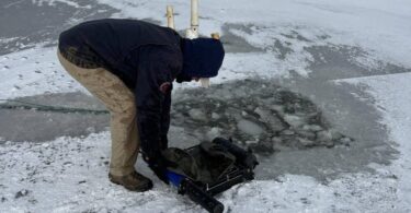 Through-ice water quality monitoring equipment being deployed on a frozen lake