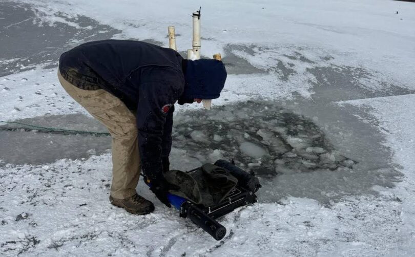 Through-ice water quality monitoring equipment being deployed on a frozen lake