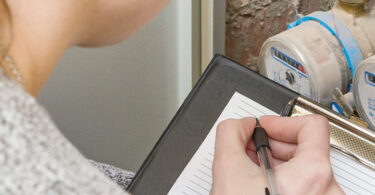 Household water meter being recorded to monitor water use and consumption