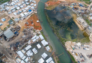 Water infrastructure damage in conflict zone showing polluted river and destroyed urban water systems