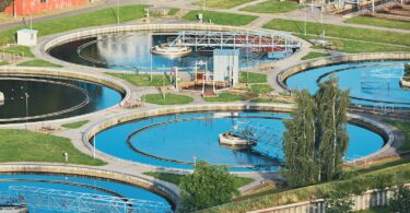 Aerial view of a wastewater treatment plant with circular clarifiers and interconnected systems, representing infrastructure where digital monitoring and optimisation technologies are applied.
