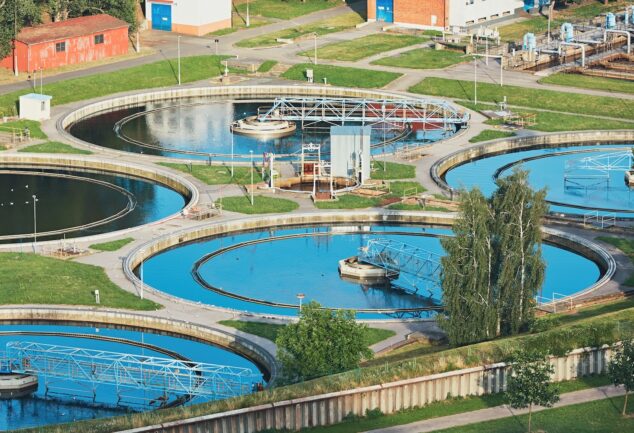 Aerial view of a wastewater treatment plant with circular clarifiers and interconnected systems, representing infrastructure where digital monitoring and optimisation technologies are applied.