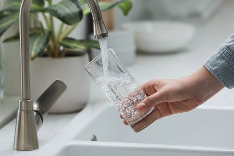 Water Saving Week tap water image showing clean drinking water flowing into glass from kitchen tap