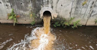 Storm overflow discharge releasing untreated wastewater into a river during a sewage pollution event.