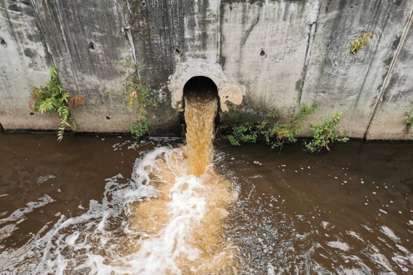 Storm overflow discharge releasing untreated wastewater into a river during a sewage pollution event.