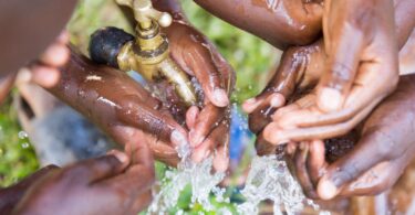 Children washing their hands with clean water from an outdoor tap
