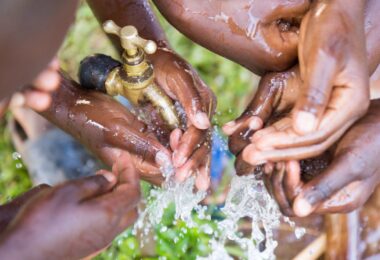 Children washing their hands with clean water from an outdoor tap