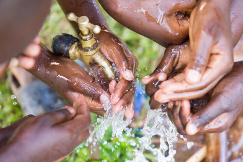 Children washing their hands with clean water from an outdoor tap