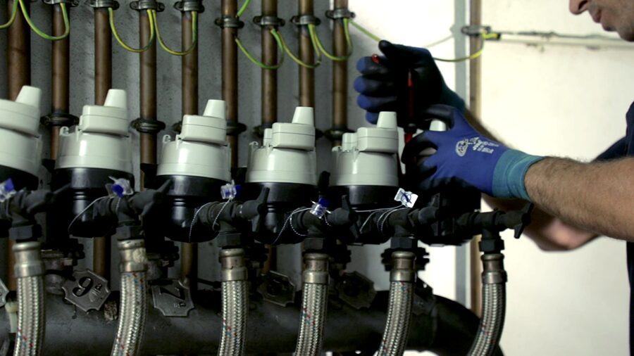 Technician working on a row of smart water meters and pipework