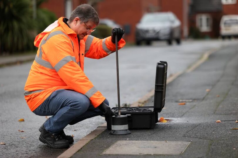 Ovarro technician using acoustic leak detection equipment to identify water network leakage in an urban street environment