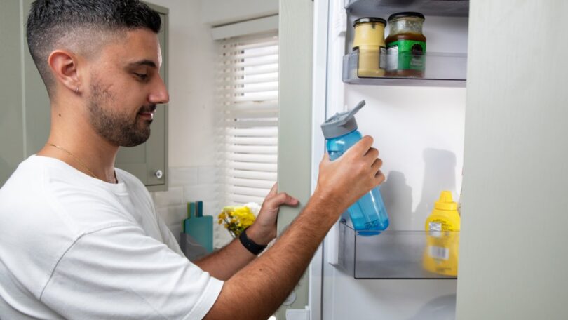 A bottle of chilled drinking water in a fridge, illustrating an appeal to use water for essential purposes during a heatwave