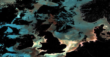 Ocean-colour satellite image of the UK and surrounding north-east Atlantic waters, showing phytoplankton, sediment and dissolved organic matter patterns captured by Copernicus Sentinel-3.