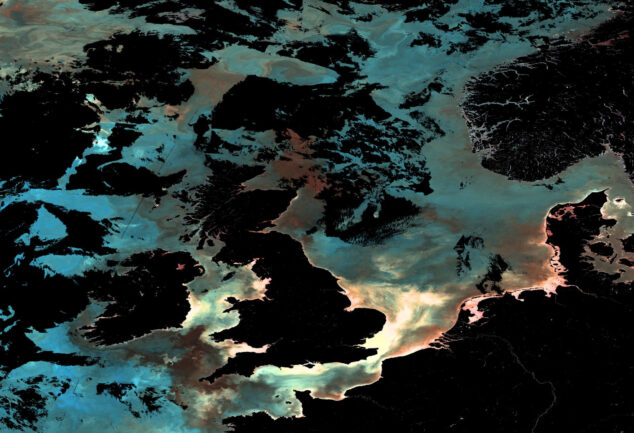 Ocean-colour satellite image of the UK and surrounding north-east Atlantic waters, showing phytoplankton, sediment and dissolved organic matter patterns captured by Copernicus Sentinel-3.