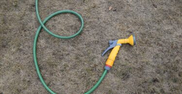 Hosepipe lying on dry grass during hot weather