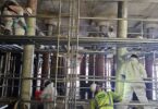 Workers applying protective coating to wharf piles during the Nashville Wharf rehabilitation project