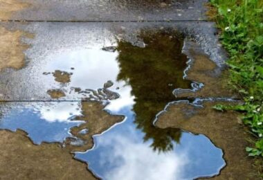 Water leakage reduction illustrated by a leaking water pipe creating a puddle on a patio