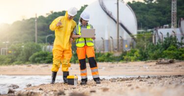 Industrial workers assessing water conditions near a processing facility
