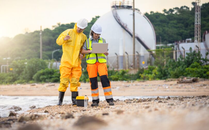 Industrial workers assessing water conditions near a processing facility