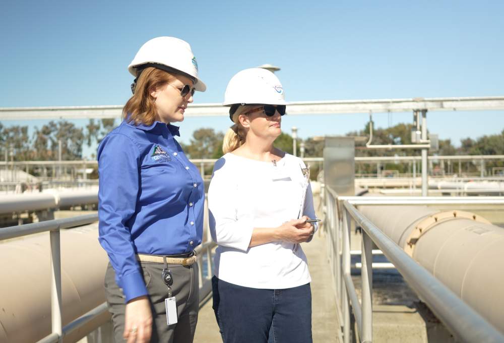 Water industry professionals at a wastewater treatment facility discussing responsible flushing and wastewater operations.