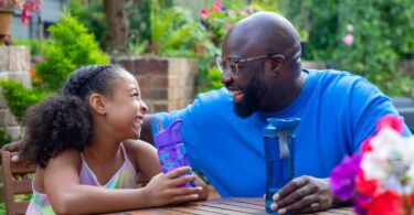 Adult and child with reusable water bottles in a garden