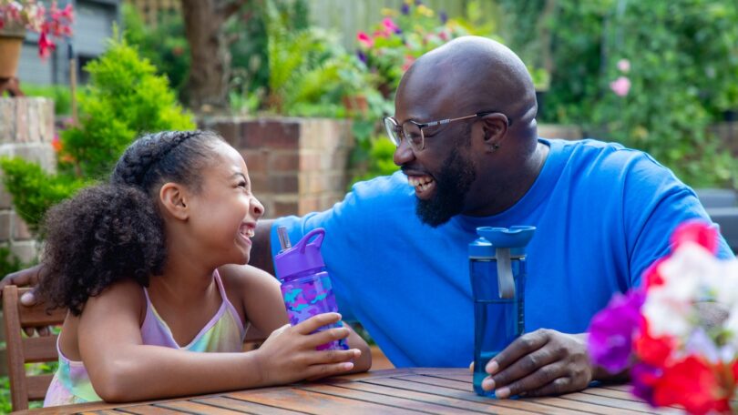 Adult and child with reusable water bottles in a garden