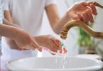 Child brushing teeth while tap water runs into a sink