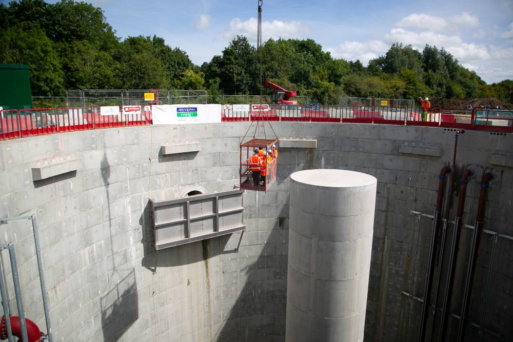 Construction workers in a suspended platform inside a large concrete storm overflow structure in Stroud