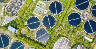 Aerial view of a sewage treatment plant with circular clarifier tanks and water basins