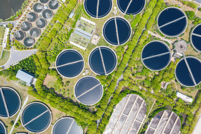 Aerial view of a sewage treatment plant with circular clarifier tanks and water basins