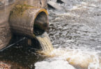 Dirty water flowing from a pipe into a river, illustrating environmental pollution.